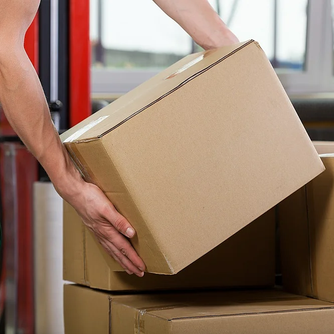 Eine Person hebt ein Paket von einem größeren Stapel Pakete herunter